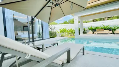 an outdoor patio with a swimming pool and an umbrella at Mouana Residence Song Khun Chalong 8910 in Phuket Town