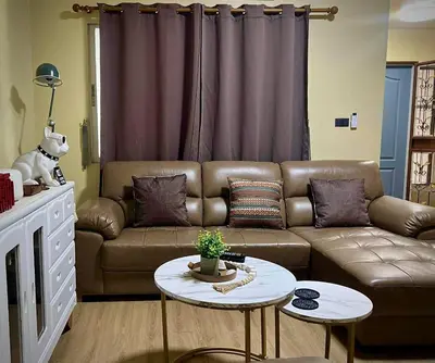 a living room with a brown couch and a table at Casa Gris with Shared Pool in Ban Bo Han