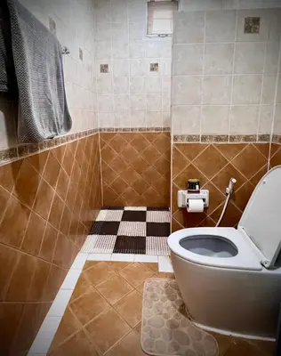 a bathroom with a toilet and a tiled floor at Casa Gris with Shared Pool in Ban Bo Han