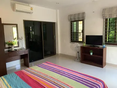 a bedroom with a bed and a tv and windows at Kata House in Kata Beach