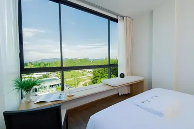 a bedroom with a bed and a large window at Condo Near Bangtao Muay Thai & MMA in Ban Thalat Choeng Thale