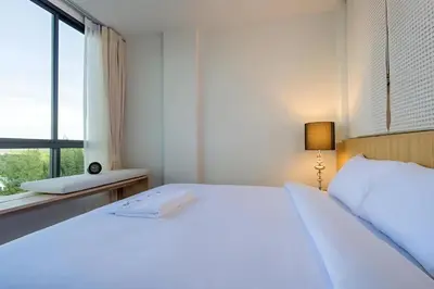 a white bed in a room with a window at Condo Near Bangtao Muay Thai & MMA in Ban Thalat Choeng Thale