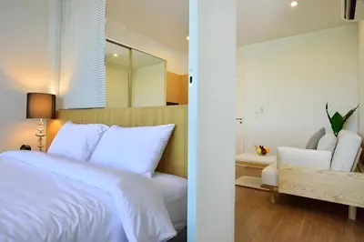 a bedroom with a white bed and a mirror at Condo Near Bangtao Muay Thai & MMA in Ban Thalat Choeng Thale