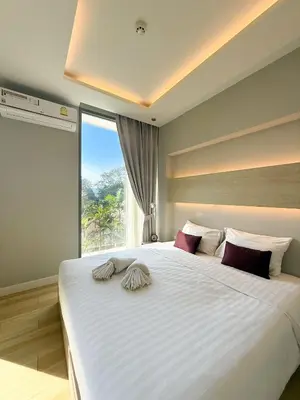 a bedroom with a large white bed with a window at The Rocco pool view in Krabi town