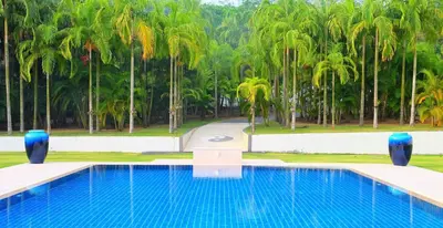 a swimming pool with palm trees in the background at Villa Tha Maphrao in Ban Pa Khlok