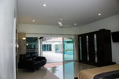 a bedroom with a bed and a chair and a sliding glass door at Villa Tha Maphrao in Ban Pa Khlok