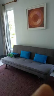 a couch with blue pillows in a room with a window at sengjan garden krabi in Ban Khlong Son