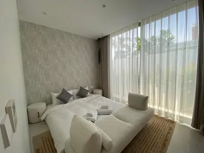 a white bedroom with a white couch and a large window at 3bdr New Modern Pool Villa Bangtao ASH-05 in Ban Phru Champa