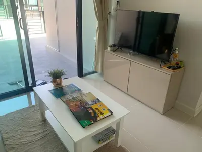a living room with a tv and a white table at 9169SiriplaceAirport in Ban Muang Mai (1)
