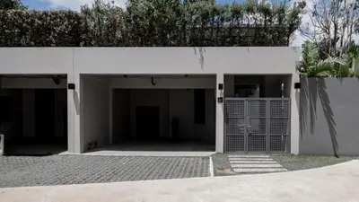 a white building with a garage with a gate at Luxury Modern Loft Villa Riverhouse in Laguna Phuket