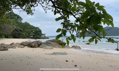 a bench on a beach with rocks and the ocean at 3-bed house with Private beach in Ban Ao Makham