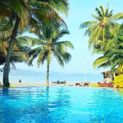 a swimming pool next to a beach with palm trees at Lamsai AC Sea House Green in Ko Yao Noi