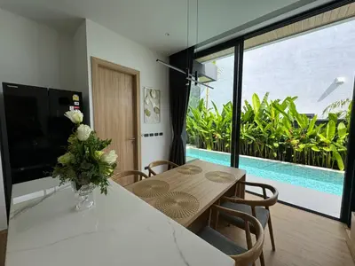 a dining room with a table and a view of a pool at Villa Aileen Naithon in Nai Thon Beach