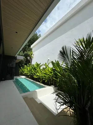 a swimming pool in front of a house with plants at Villa Aileen Naithon in Nai Thon Beach