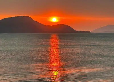 a sunset over the water with a mountain in the background at Sea View & Pool Apartment in Phuket Town