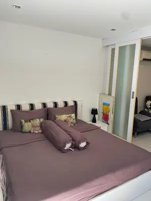 a large bed with purple sheets and stuffed animals on it at Sea View & Pool Apartment in Phuket Town
