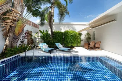 a swimming pool with two blue chairs and a house at The Greens Phuket Villa with swimming pool 18 in Ban Saiyuan (1)