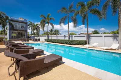 a swimming pool with lounge chairs and palm trees at Modern Comfort in Paradise - Villa Argent 6 with 3BR and Access to Tropical Pool in Thalang