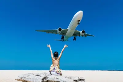 a person sitting on a beach with an airplane at Modern Comfort in Paradise - Villa Argent 6 with 3BR and Access to Tropical Pool in Thalang