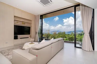 a living room with a couch and a large window at Penthouse Luxurious Seaview Patong in Patong Beach