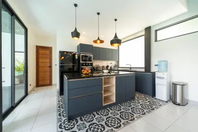 a kitchen with blue cabinets and a tile floor at Innovative 4BR Villa Sunset Garden 1 with Oxygen Pool in Rawai Beach