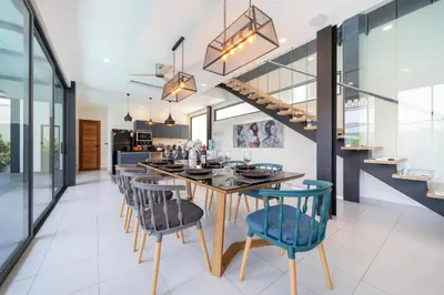 a dining room with a table and chairs and a staircase at Innovative 4BR Villa Sunset Garden 1 with Oxygen Pool in Rawai Beach