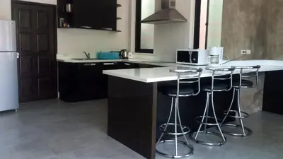 a kitchen with black cabinets and a counter with stools at Villa Patong 3 Chambres in Patong Beach