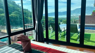 a room with a large window with a view of the mountains at Villa Patong 3 Chambres in Patong Beach