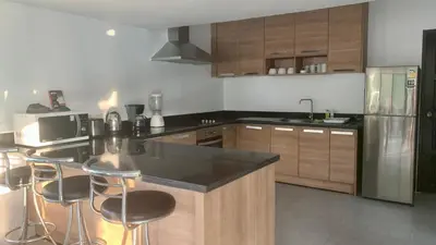 a kitchen with wooden cabinets and a black counter top at Villa Loma 3 Chambres in Patong Beach