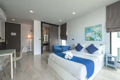 a bedroom with a large bed and a blue chair at Vibrant Life at 4BR Pool Villa, Kata - UTK3 in Kata Beach