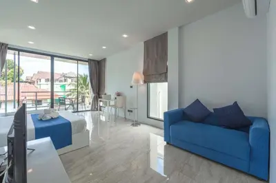 a living room with a blue couch and a bedroom at Vibrant Life at 4BR Pool Villa, Kata - UTK3 in Kata Beach
