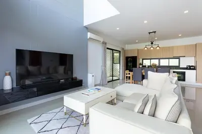 a living room with a white couch and a tv at Phuket Nai Han Beach Villa with Pool in Rawai Beach