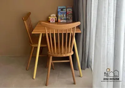 a wooden table and two chairs at a table with a curtain at 202 HOUSE near Bangtao Muay Thai & MMA in Ban Thalat Choeng Thale