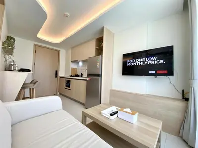 a living room with a white couch and a tv at Fantasea Condo - Kamala in Kamala Beach
