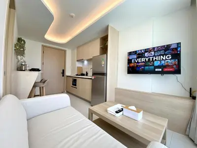 a living room with a couch and a tv on the wall at Fantasea Condo - Kamala in Kamala Beach