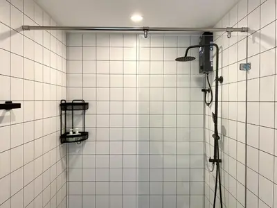a shower in a bathroom with white tiles at Fantasea Condo - Kamala in Kamala Beach