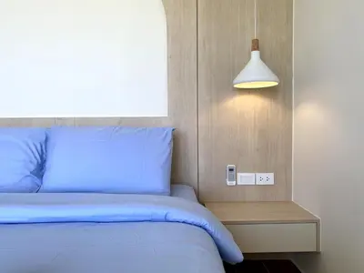 a bedroom with a blue bed and a light switch at Fantasea Condo - Kamala in Kamala Beach