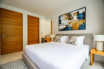 a bedroom with a large white bed and a wooden door at 3BR Pool Villa at Botanica Modern Loft in Bangtao in Bang Tao Beach