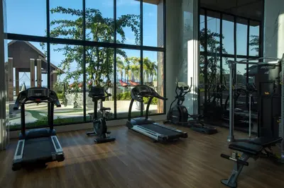 a gym with several treadmills and elliptical machines at 1bdr Seaview Apartment near Surin Beach in Surin Beach