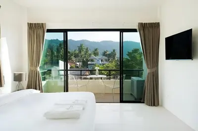 a bedroom with a bed and a balcony with a view at Apartments Near Bangtao Muay Thai & MMA in Ban Thalat Choeng Thale