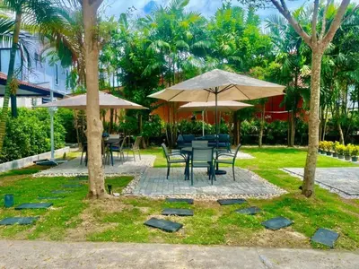 a table and chairs with umbrellas in a garden at Apartments Near Bangtao Muay Thai & MMA in Ban Thalat Choeng Thale