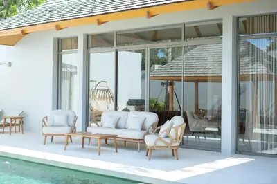 a patio with white furniture next to a pool at Anchan Flora by Villacarte in Ban Phru Champa