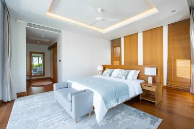 a bedroom with a large bed and a blue chair at Anchan Flora by Villacarte in Ban Phru Champa