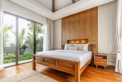a bedroom with a large bed and a large window at Anchan Flora by Villacarte in Ban Phru Champa