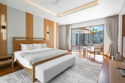 a bedroom with a large bed and a living room at Anchan Flora by Villacarte in Ban Phru Champa