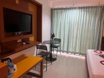 a living room with a table and chairs and a television at Arisa Hotel Patong Beach in Patong Beach