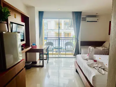 a hotel room with a bed and a tv and a balcony at Arisa Hotel Patong Beach in Patong Beach