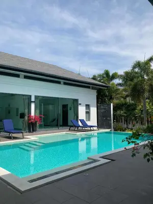 a swimming pool with two blue chairs and a house at Luxury Pool Villa Nai Harn in Ban Saiyuan (1)