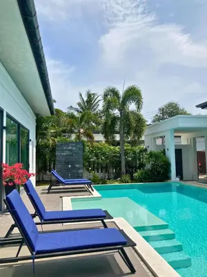 a swimming pool with blue lounge chairs next to a house at Luxury Pool Villa Nai Harn in Ban Saiyuan (1)