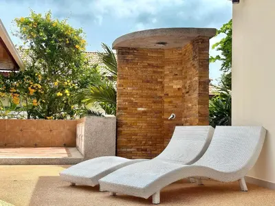 a white chair sitting in front of a brick wall at Chuan SeaFront Villa Rawai Phuket in Rawai Beach